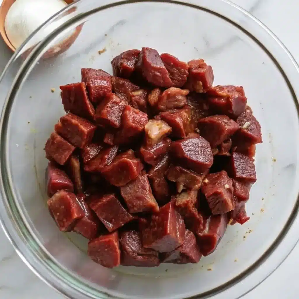 Steak cubes being tossed in a bowl with marinade and spices
